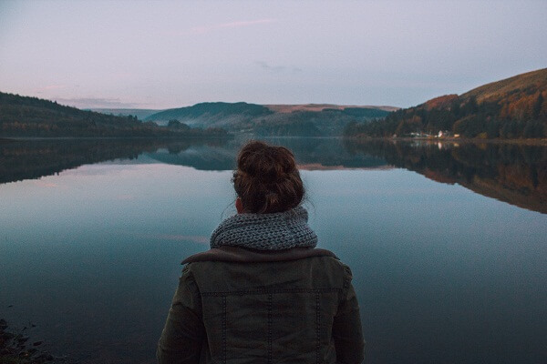 Kobieta patrzy na spokojny krajobraz z jeziorem
