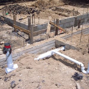 Fundamenty budynku z betonowymi ławami i instalacjami rurowymi przed zasypaniem